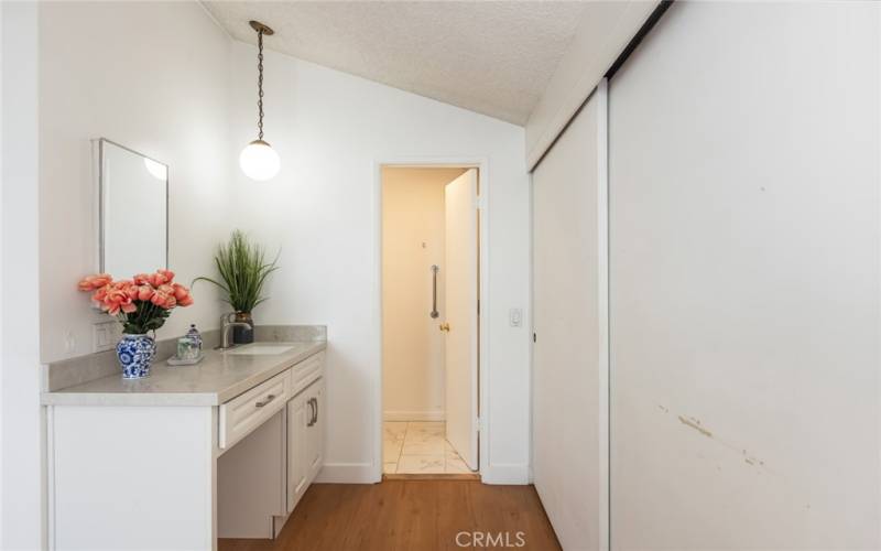 vanity in primary bedroom leading to private bath