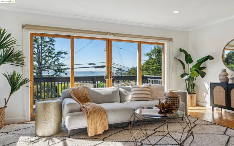 The living room features original random plank hardwood flooring and large doors out to the deck.