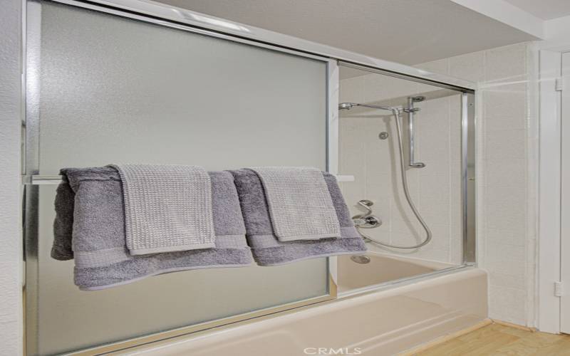 The guest bathroom has a shower over the tub and enclosure.