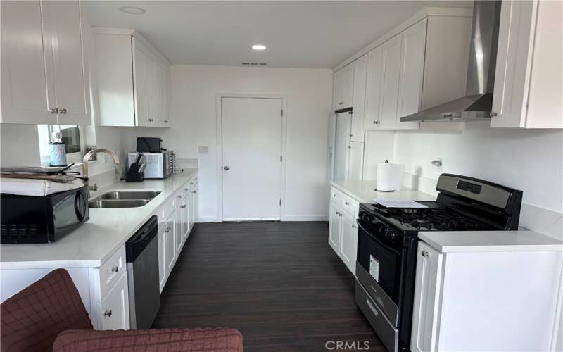 Kitchen equipped with all appliances: dishwasher, gas range, microwave, refrigerator.