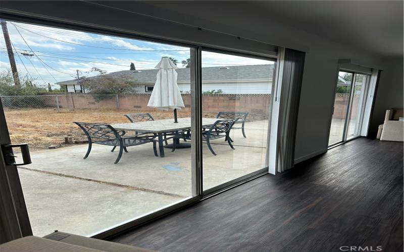 Sliding glass doors from living room lead to hardscape in background. Table in backyard is included.