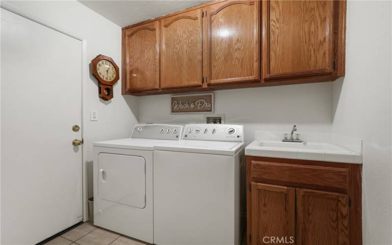 Indoor laundry room with convenient sink and cabinets.