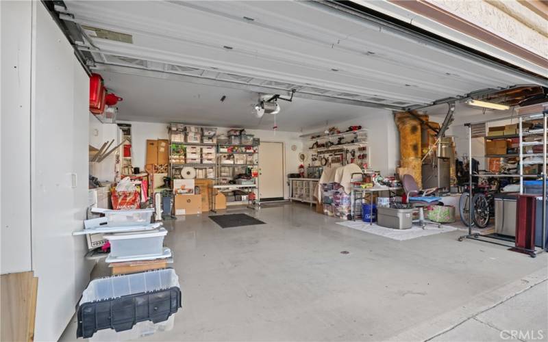 The 2+ car garage has a golf cart or storage area on the right with lots of built-in cabinets and a workbench.