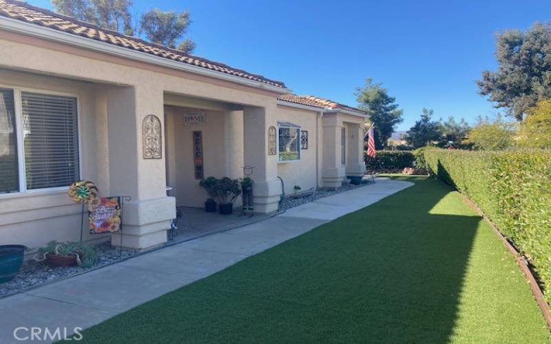 The entry area is so inviting with this lush artificial turf and a privacy hedge all around the home.