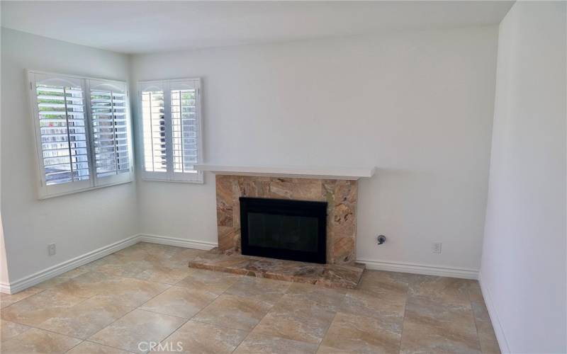 Fireplace room with mantel, looks out to lush green backyard