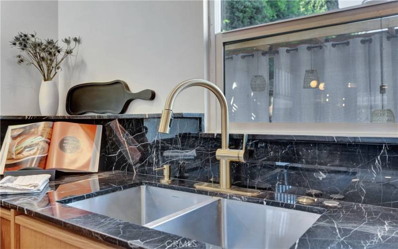 Kitchen sink with mid-century modern brass fixtures and beautiful marble countertops