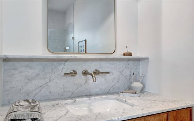 Bathroom 2 with marble counters and wall-mounted brass faucets