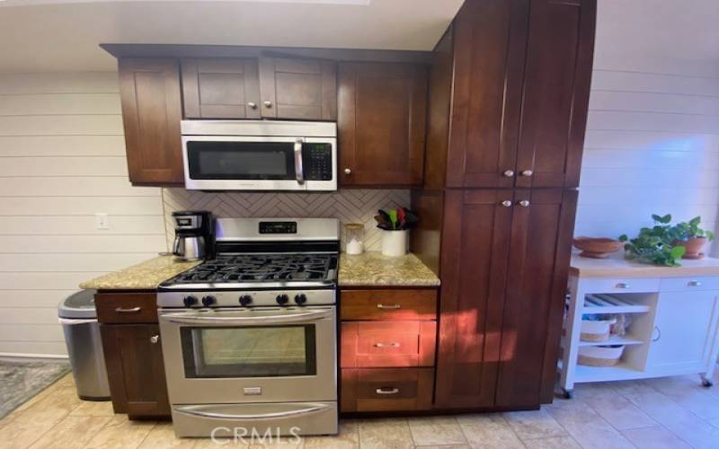 Gas stove with microwave and pantry cabinets.