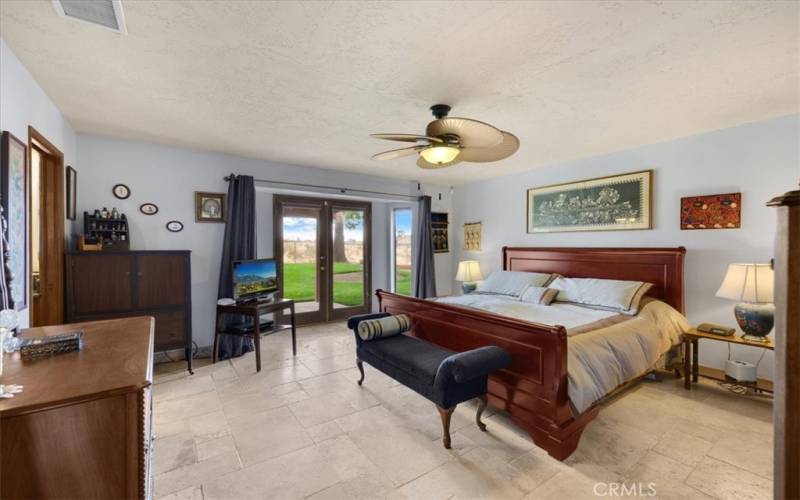 Primary Home - Primary Bedroom with Travertine Flooring and French Door Access to the Backyard Covered Patio