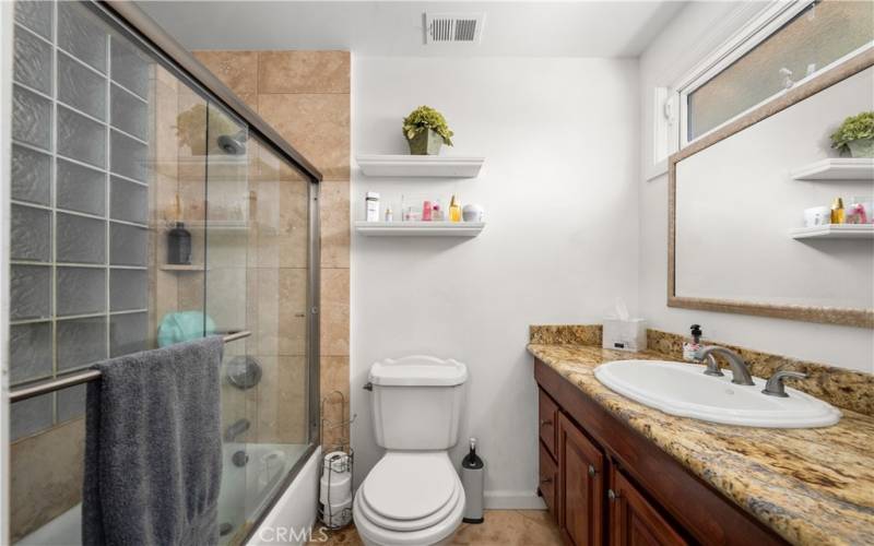 Primary bath with granite counter tops, shower in a tub, glass doors and a window for ventilation.