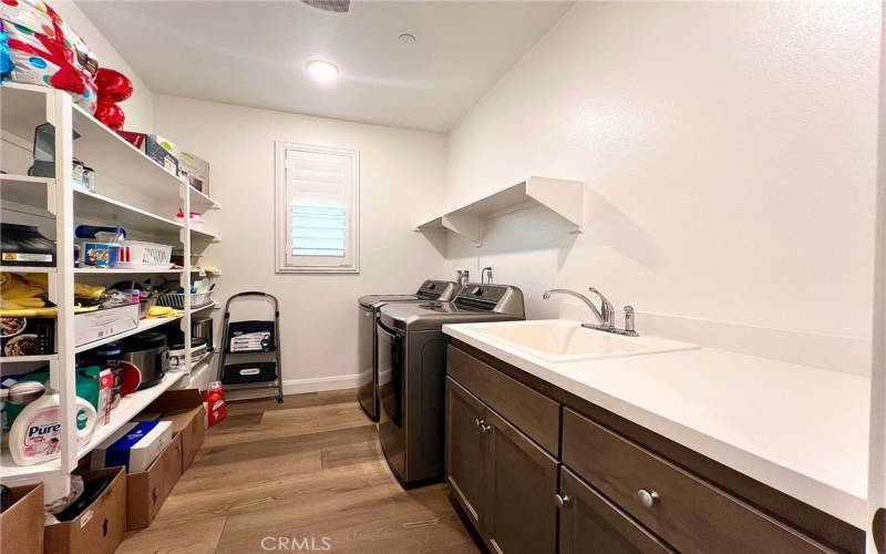 Spacious laundry with sink, shelving, folding table, and modern finishes