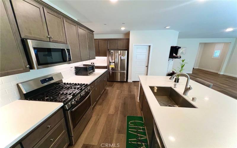 Spacious kitchen with a sleek one-compartment sink, modern backsplash, and a well-placed pantry—designed for both style and convenience.