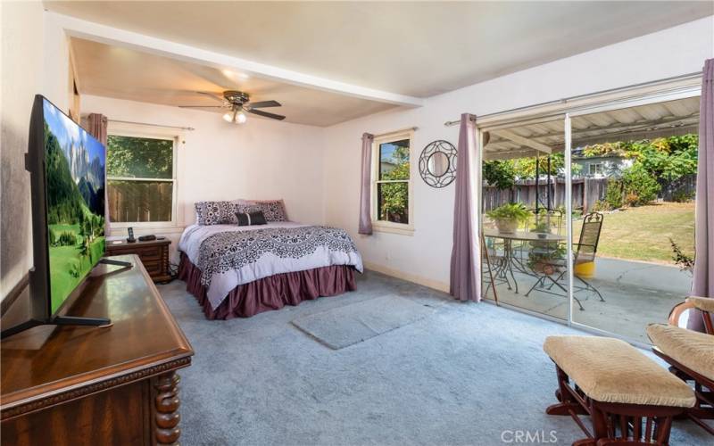 Big bedroom in back of house with sliding glass door to outside patio