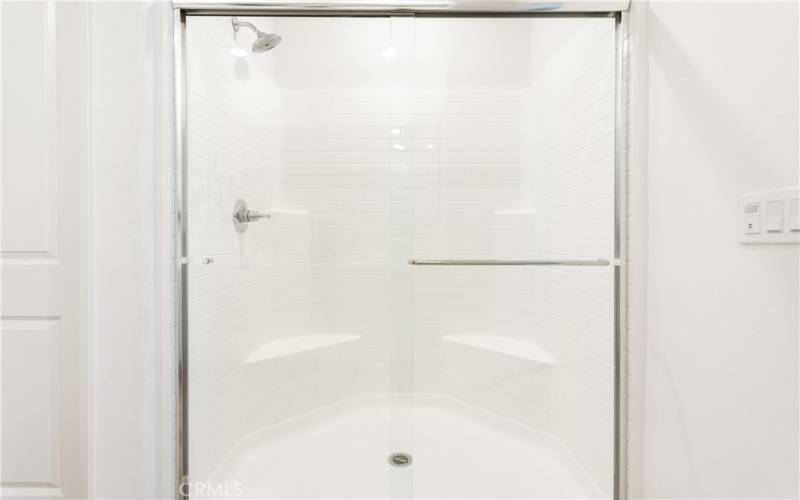 Large step-in shower with sitting area.