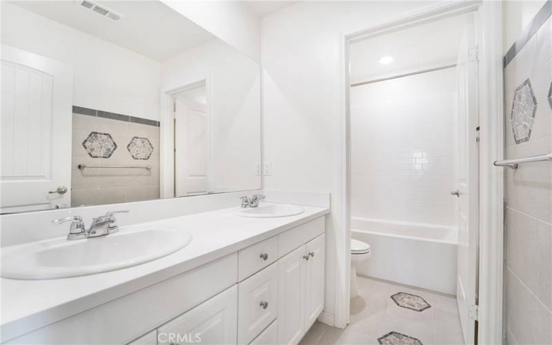 Upstairs bathroom features dual sinks, and custom designer tile work.