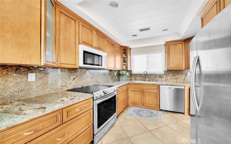 Upgraded kitchen includes custom cabinetry, granite countertops and backsplash, Bosch dishwasher, stainless steel Samsung refrigerator, Jenn-Air Microwave, Ivation wine fridge and Samsung electric cooktop and oven.