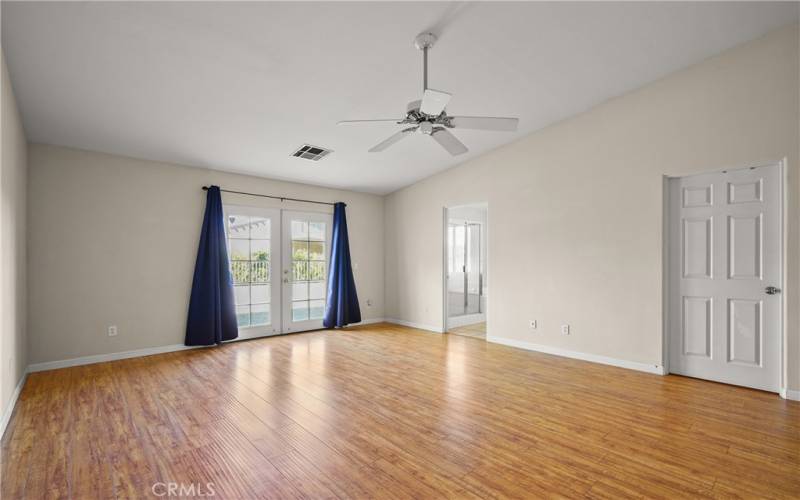 Bright, large primary bedroom with double doors leading to back yard