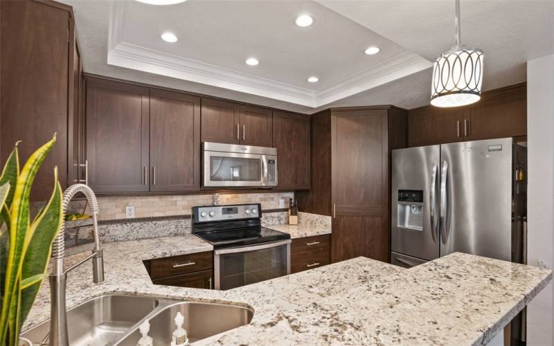 Upgraded kitchen with granite counters, custom cabinetry and large pantry