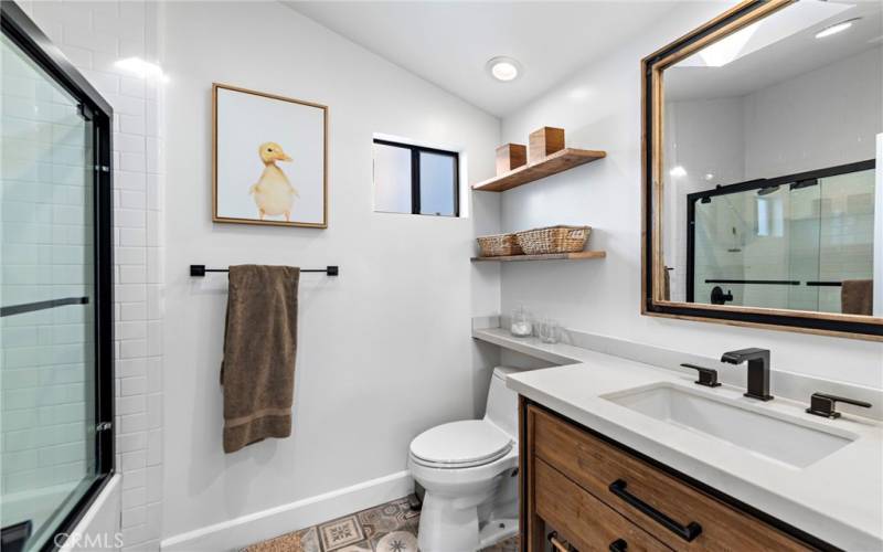 Upgraded primary bath with quartz counters, custom vanity, and tile backsplash in shower/tub