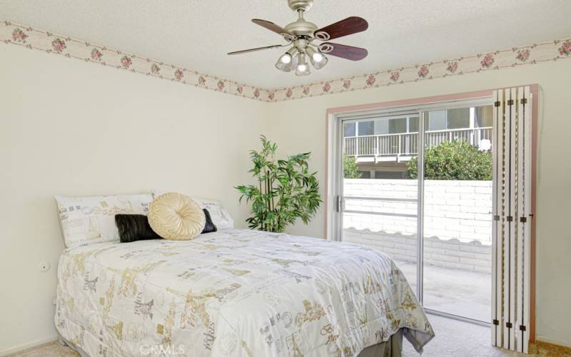 Pretty guest bedroom has a sliding glass door that overlooks the patio.  Nice shutters provide privacy.  The ceiling fan helps to keep the cool ocean breezes circulating.