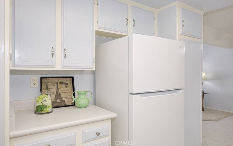 There's a nice cabinet on the left of the refrigerator and a nice pantry on the right.