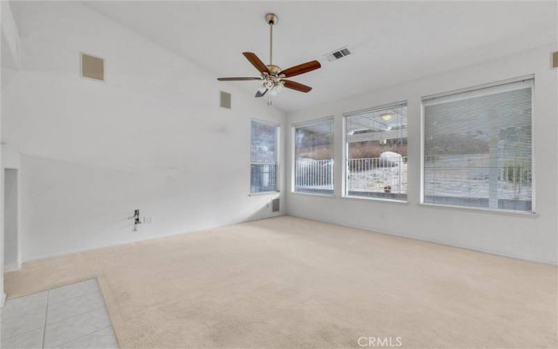 Large family room with ceiling fan and installed speakers.