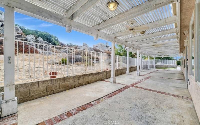 Long patio with patio cover leading to the pool area.