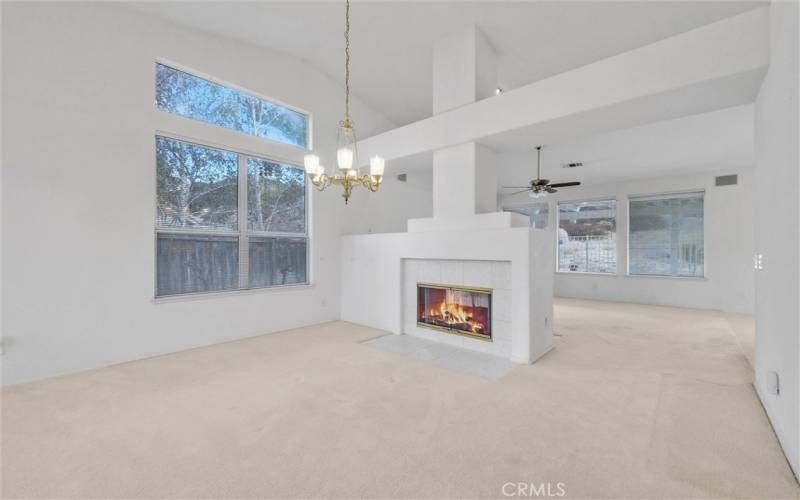 Living room and family room separated by double sided fireplace with gas log set.