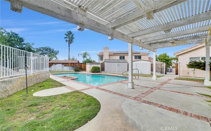 Patio area with beautiful pool and wrought iron fencing.