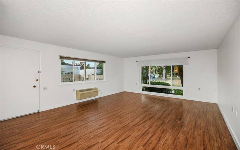 Large living room with giant picture window and second large window to let light and greenery in.