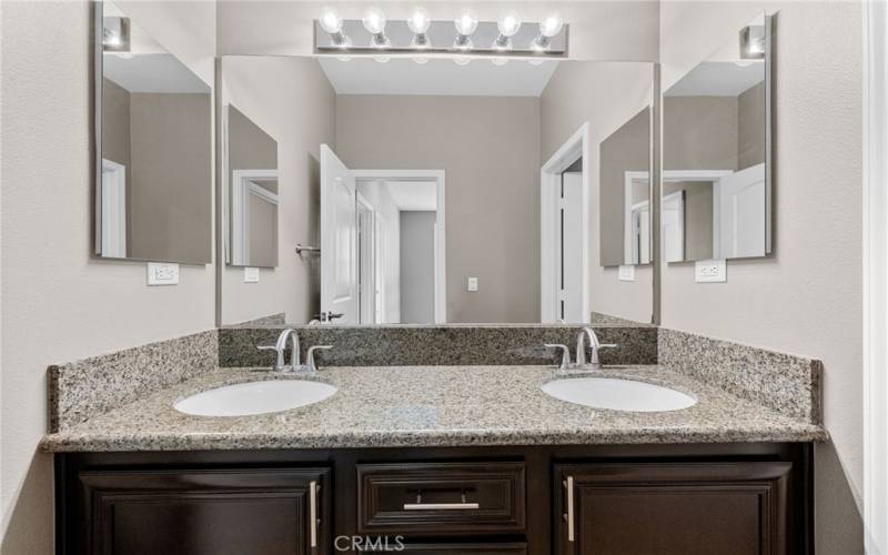 The secondary bathroom features dual medicine cabinets, tile flooring and a granite vanity countertop.