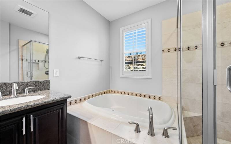 The primary bathroom features a generous walk-in shower, soaking tub, double vanity and tile flooring.
