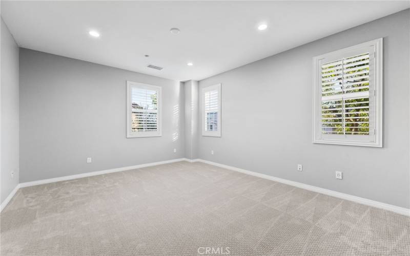 The primary bedroom features recessed LED lighting, an alcove for furniture/TV, multiple windows and custom paint.