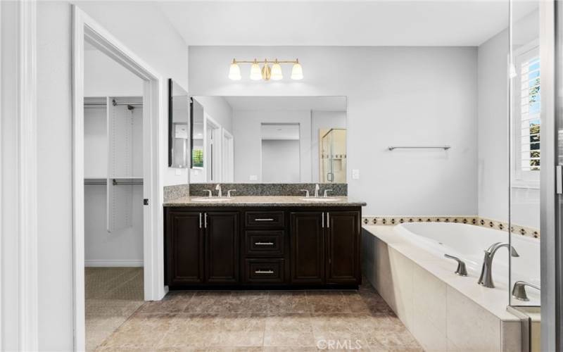 The primary bathroom features a generous walk-in shower, soaking tub, double vanity and tile flooring.
