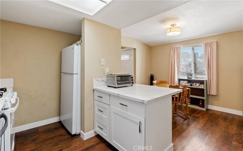 The updated kitchen enjoys newer, bright-white cabinets and a handsome quartz countertop with extended counter space to include a breakfast bar. Bonus, the refrigerator stays!