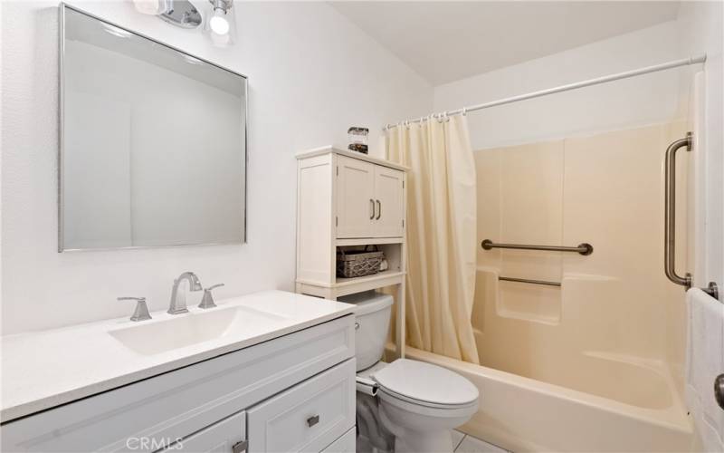 Centrally located, there is a full bathroom that has newer cabinets, a lovely solid surface counter, and a full tub/shower with acrylic enclosure and grab bars.