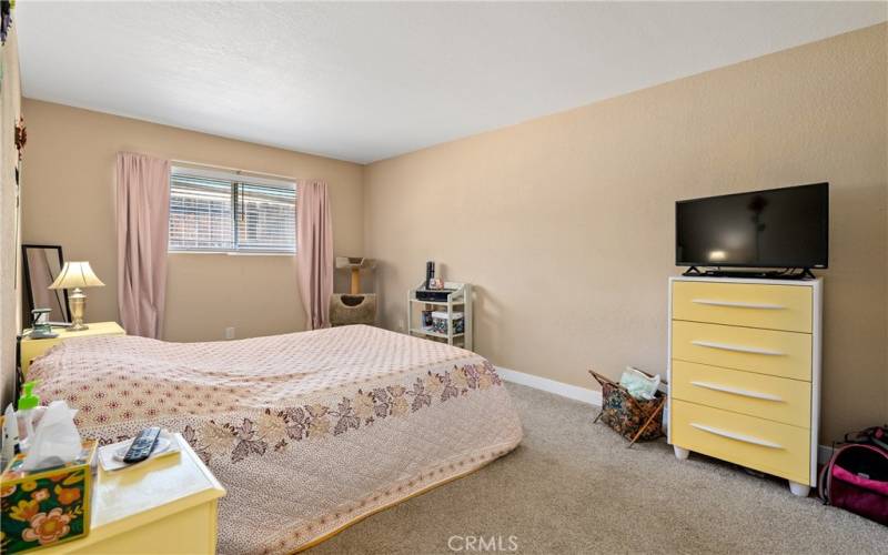 This spacious, carpeted primary bedroom offers its own sense of seclusion placed in the back of the home. It has a single closet with sliding doors.