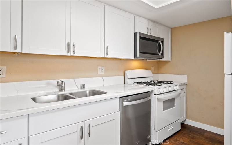 This kitchen is stylish and functional with plenty of prep stations, cabinets, and a built-in microwave above the stove.