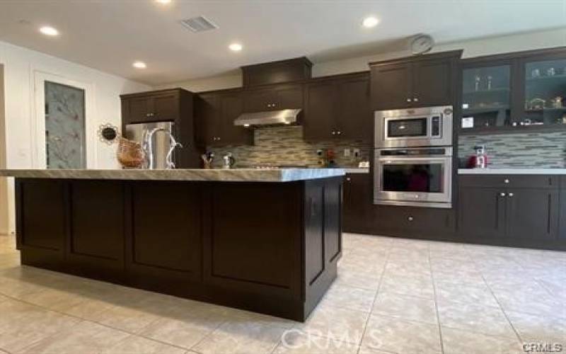 This kitchen is large enough for a table and chairs, and has an island with quartz countertops. The appliances are stainless steel.