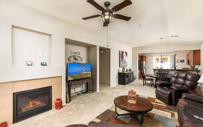 Family room includes cozy fireplace and media niche.  Looking into dining area and adjoining kitchen.