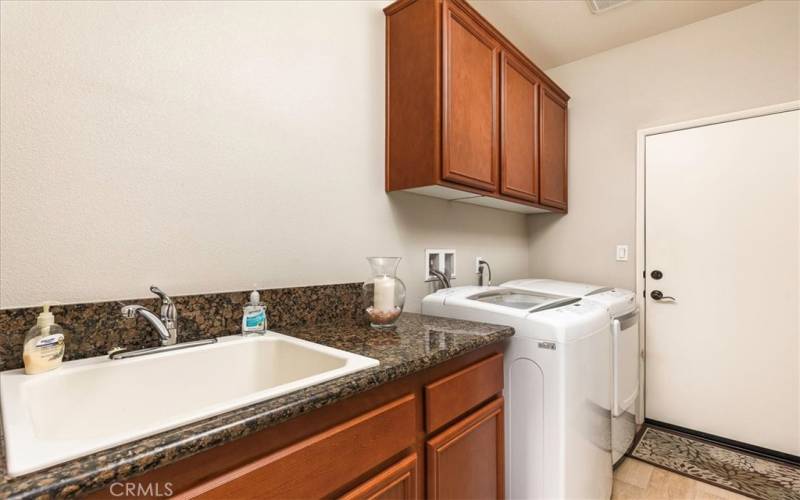 Indoor laundry room with built in sink and cabinets.