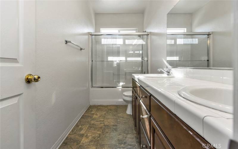 Upstairs guest bath #2 with shower in tub and dual sinks.