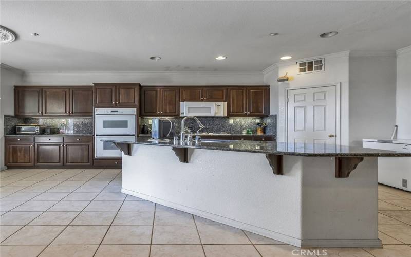 Beautiful kitchen with large island, granite counters and full backsplash, and walk-in pantry.