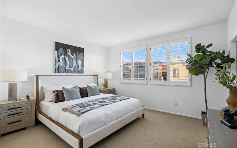 Bedroom w/ classic Plantation Shutters covering oversized windows with loads of sunlight peering through