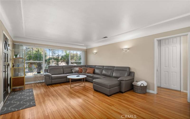 Generous sized living room with original hardwood flooring and a beautiful oversized window bringing in an abundant of natural light.