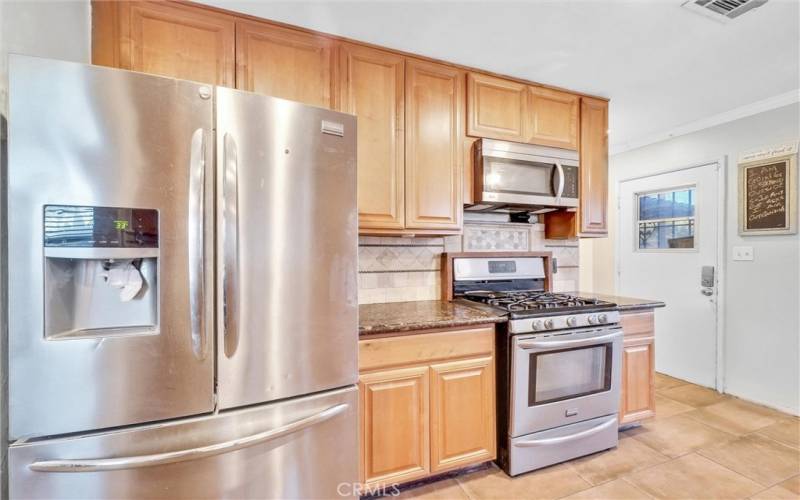 Stainless Steel appliances. Door leading to backyard.