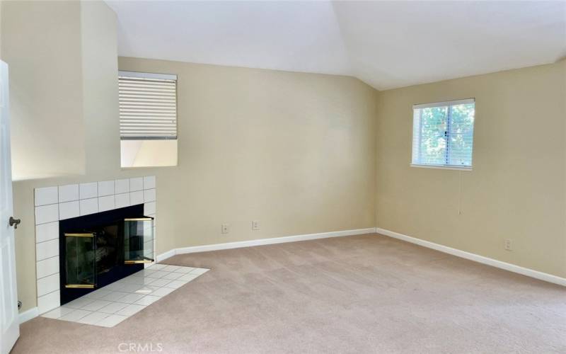 Spacious primary bedroom with vaulted ceilings and fireplace