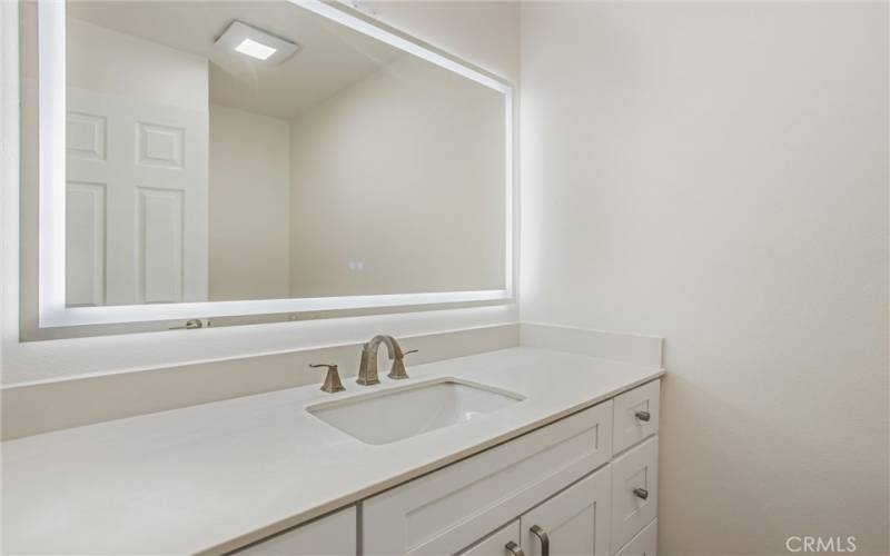 Guest bath on first level with designer mirror, vanity, faucet, & toilet