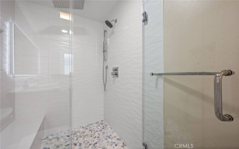 Primary bath room with double sinks and walk-in shower with seat and rain shower