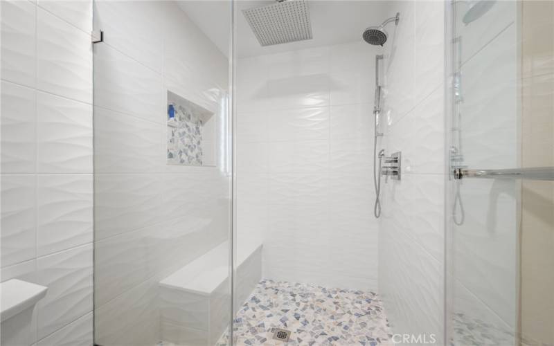 Primary bath room with double sinks and walk-in shower with seat and rain shower